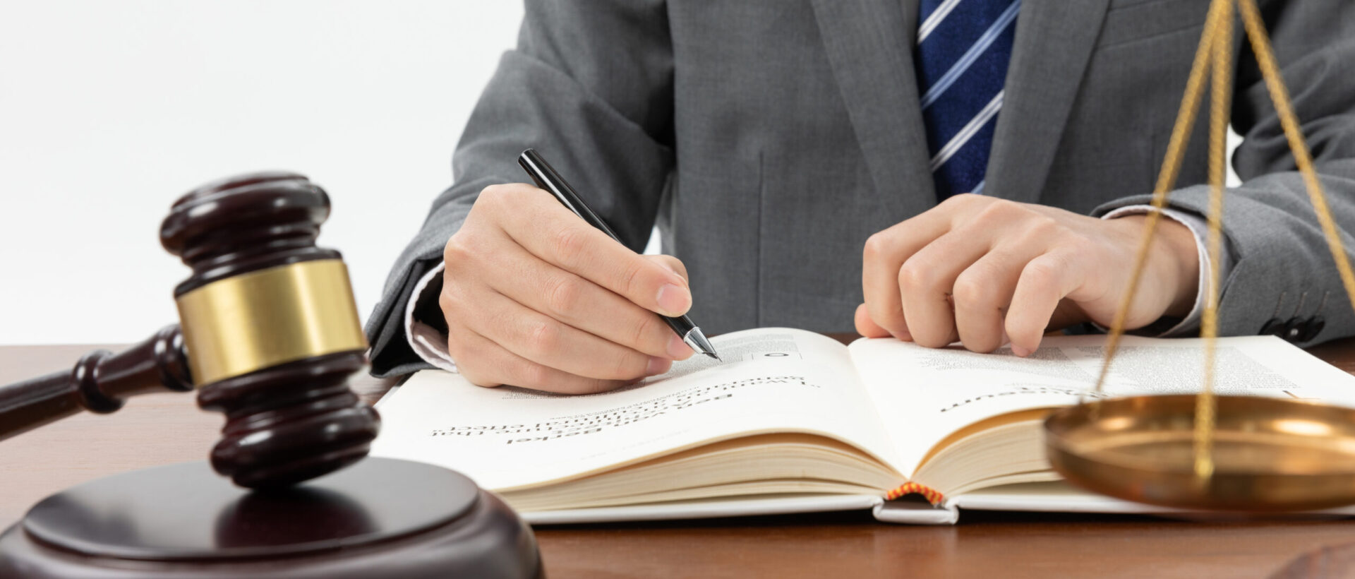 closeup-shot-person-writing-book-with-gavel-table